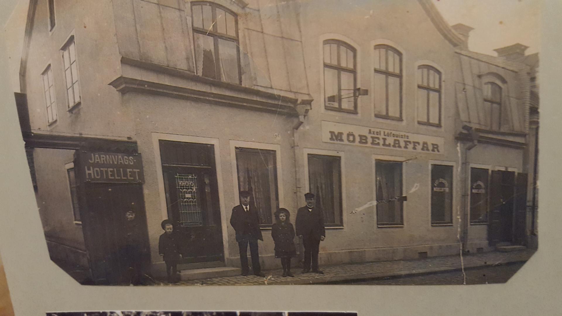 Axel Löfqvist Möbelaffär, Adelsgatan 9, efter ombyggnaden av vindsvåningen. Axel Löfqvist står bedvid dörren, svärsonen Frans Dahlberg till höger samt tre av Axels barnbarn, syskonen Dahlberg, Erik, Einar och Sara. Foto omkring 1910, tillhörande Sara Lundberg.